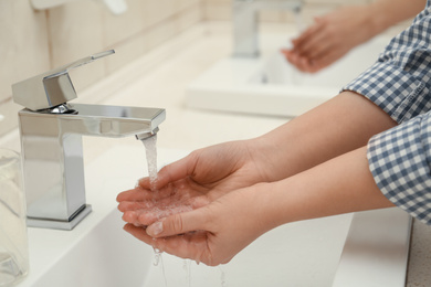 Photo of Woman washing hands with antiseptic soap in public restroom, closeup. Virus prevention