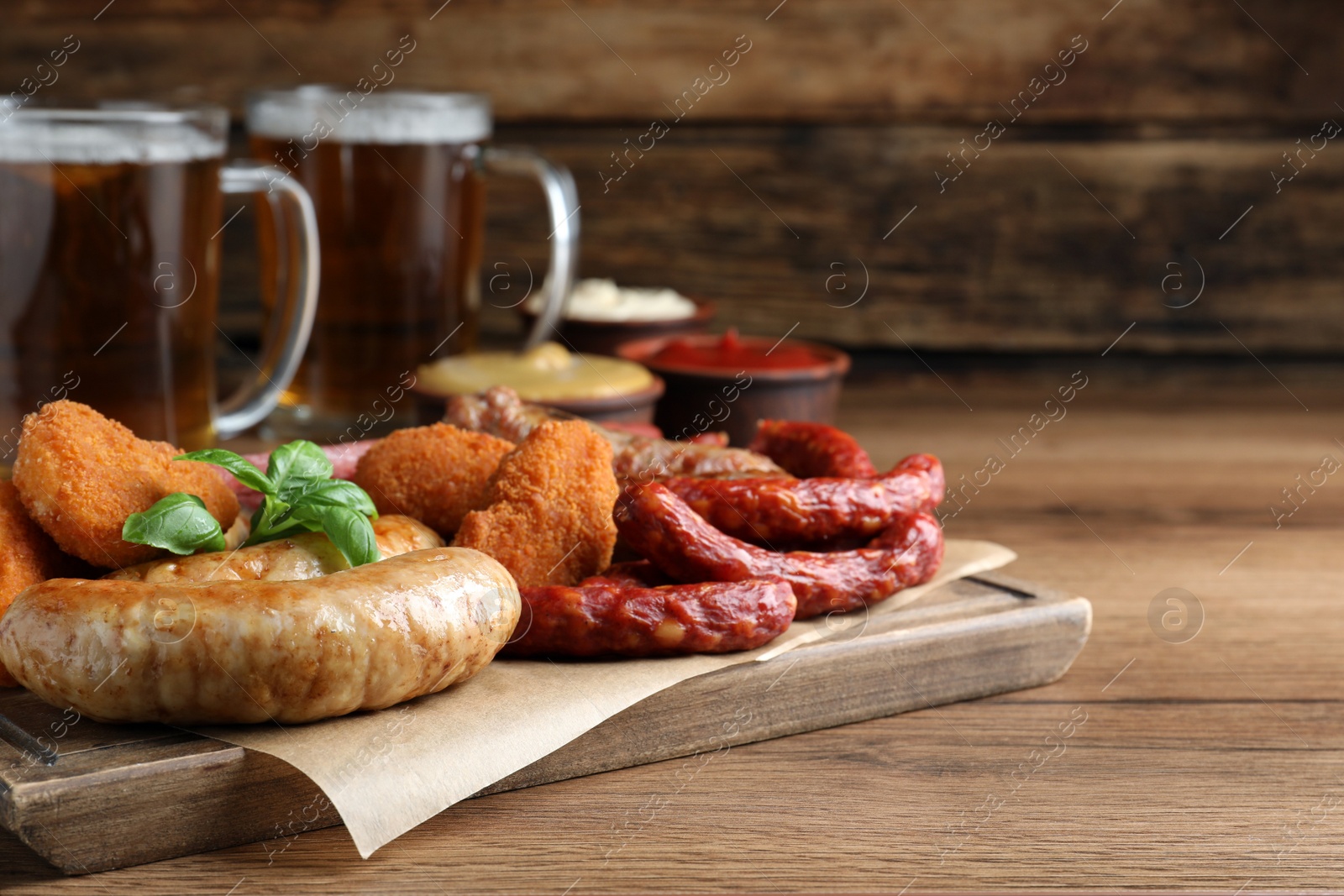 Photo of Set of different tasty snacks and beer on wooden table, space for text