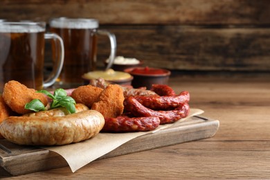 Set of different tasty snacks and beer on wooden table, space for text