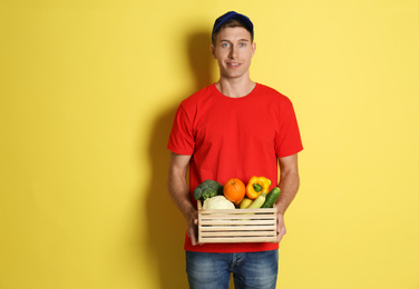 Photo of Courier with fresh products on yellow background. Food delivery service