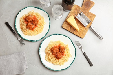 Delicious pasta with meatballs and tomato sauce on grey background, flat lay