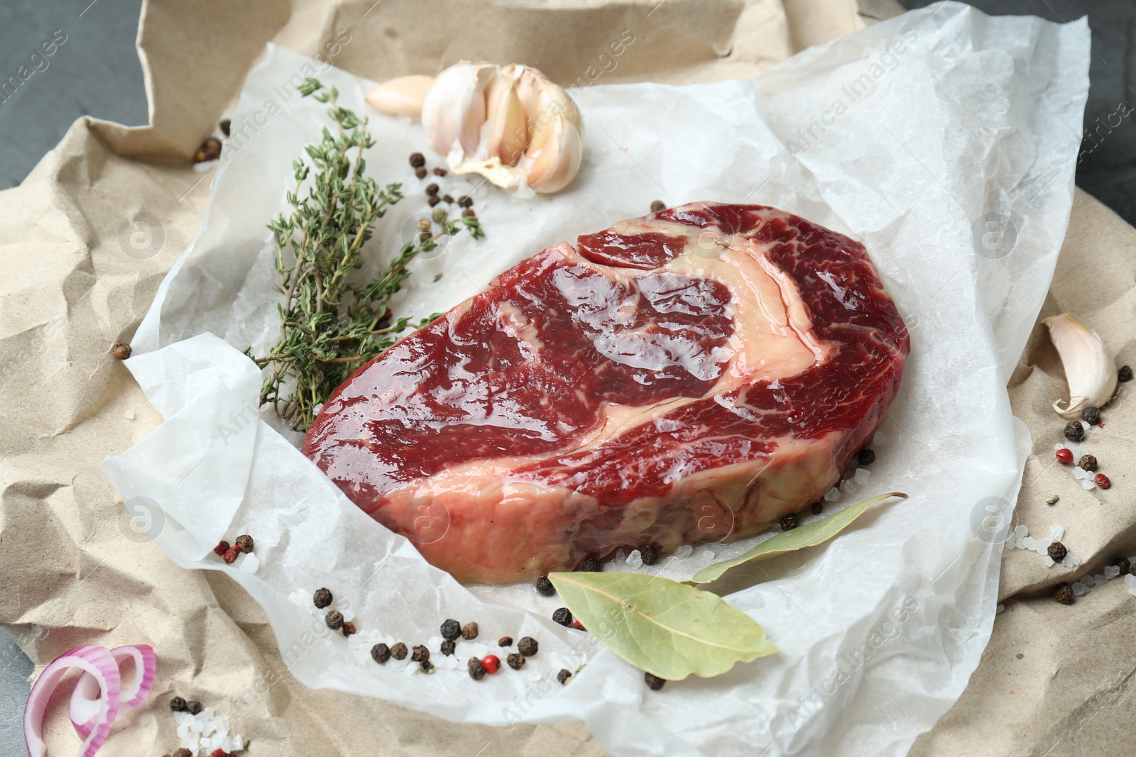 Photo of Piece of raw beef meat and spices on parchment