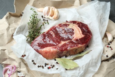 Photo of Piece of raw beef meat and spices on parchment