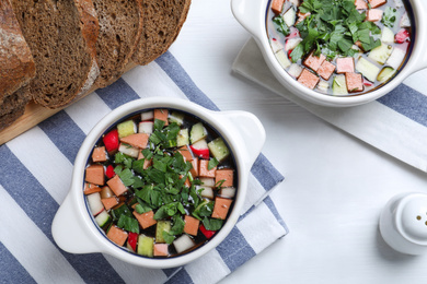 Photo of Delicious cold okroshka with kvass served on white table, flat lay. Traditional Russian summer soup