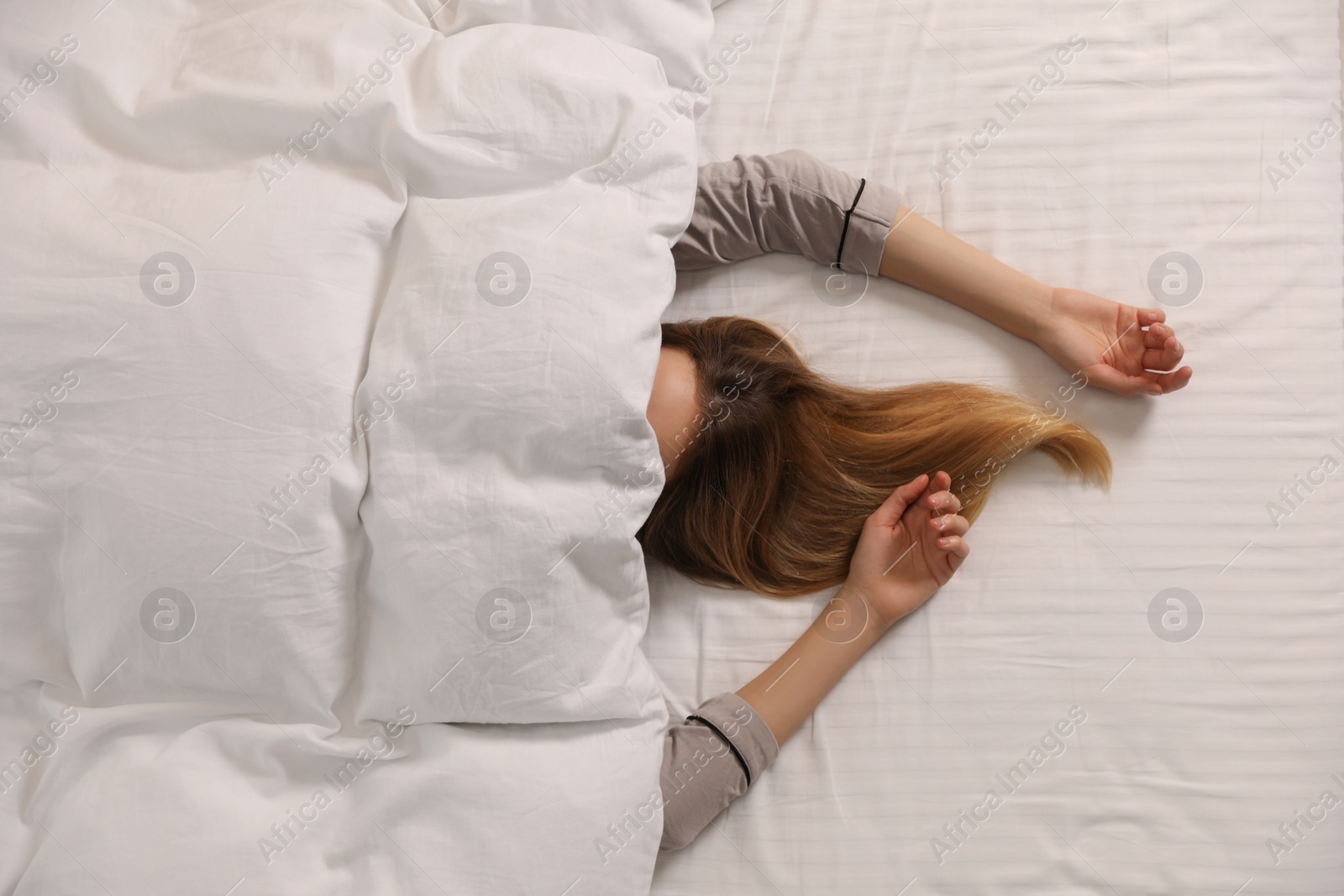 Photo of Woman under warm white blanket in bed, top view