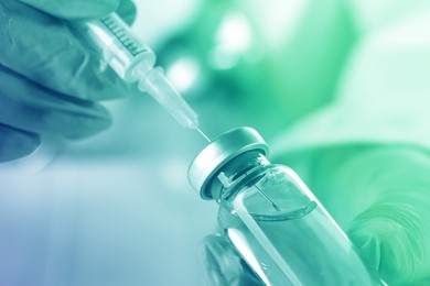 Image of Doctor filling syringe with medication from vial, closeup. Color toned