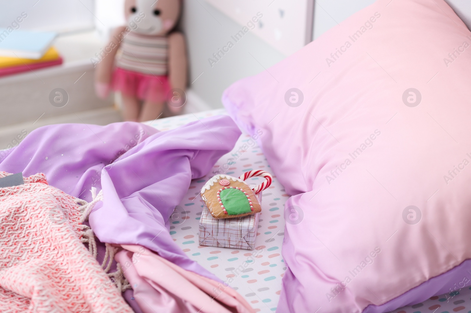 Photo of Gift box with candy cane and gingerbread on bed in children's room. St. Nicholas Day