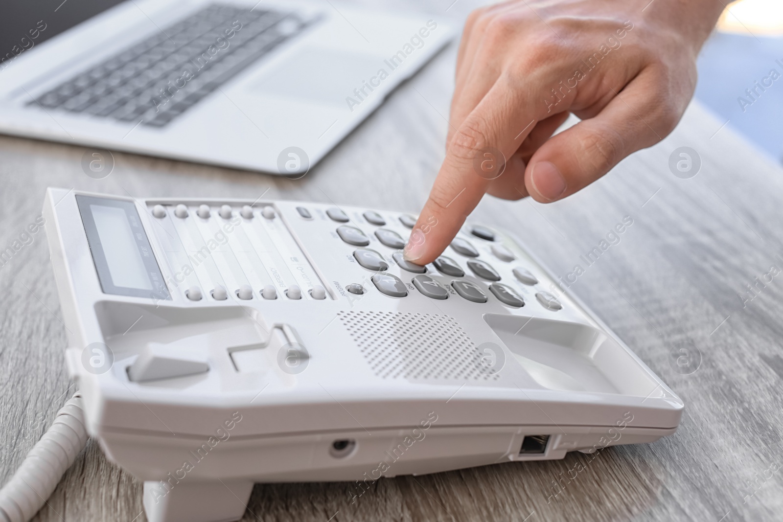 Photo of Man dialing number on telephone at workplace