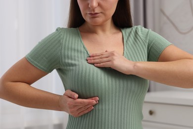 Photo of Mammology. Woman doing breast self-examination indoors, closeup