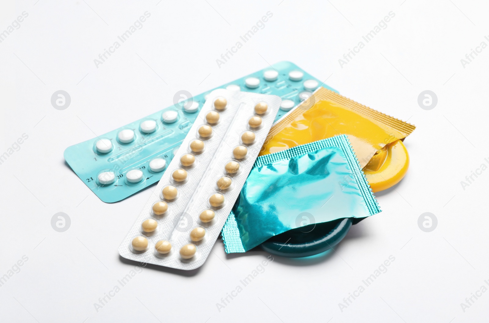 Photo of Condoms and birth control pills on white background, closeup. Safe sex concept