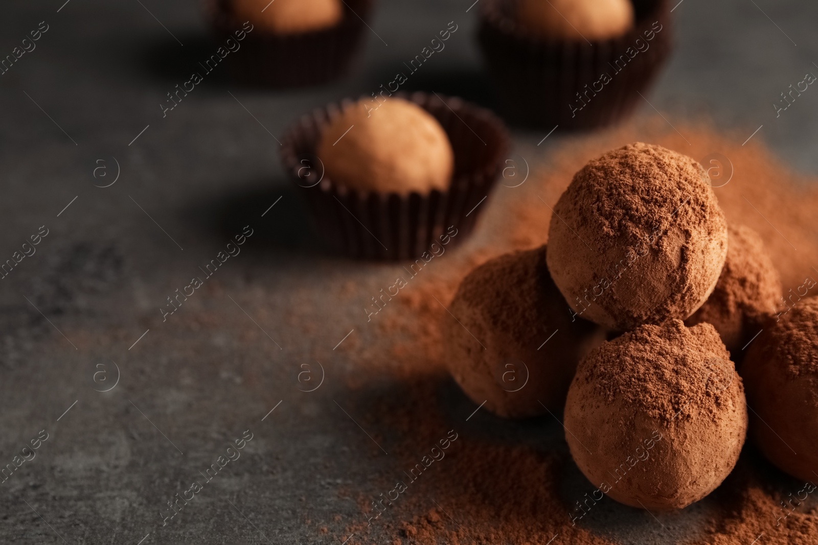 Photo of Tasty chocolate truffles powdered with cocoa on grey background, space for text