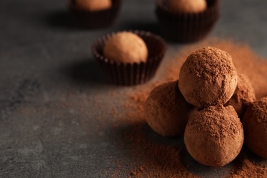 Photo of Tasty chocolate truffles powdered with cocoa on grey background, space for text