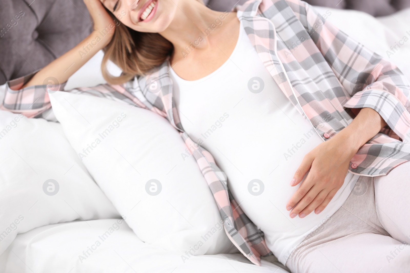 Photo of Happy pregnant woman lying in bed at home, closeup