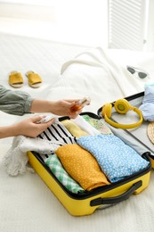 Woman packing suitcase for trip on bed, closeup