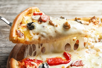 Photo of Shovel with slice of delicious hot pizza over table, closeup