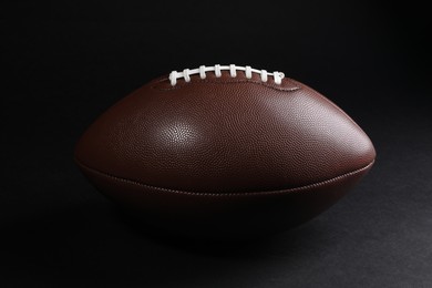 Photo of Leather American football ball on black background