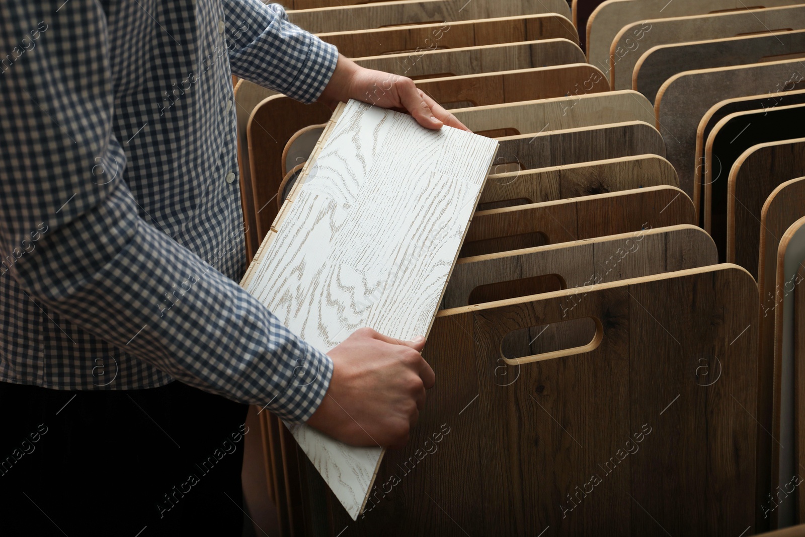 Photo of Man with sample of light wooden flooring in shop, closeup