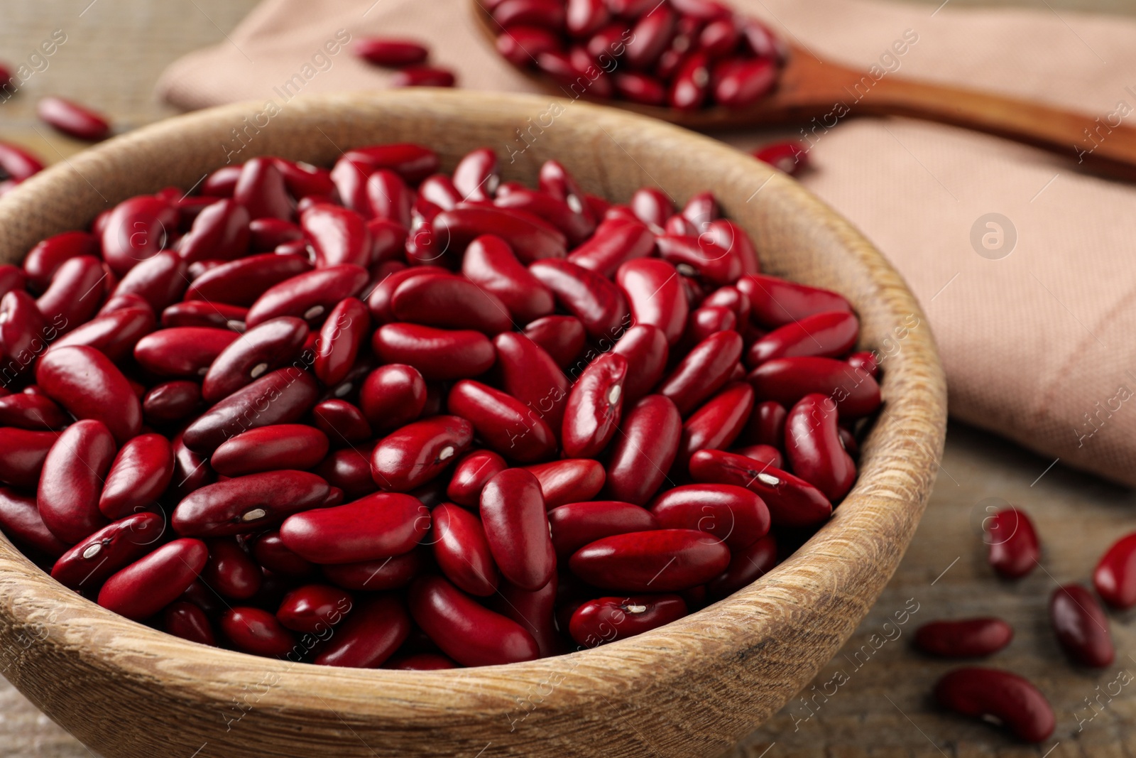 Photo of Raw red kidney beans in wooden bowl on table, closeup