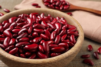 Raw red kidney beans in wooden bowl on table, closeup