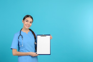 Photo of Portrait of medical assistant with stethoscope and clipboard on color background. Space for text