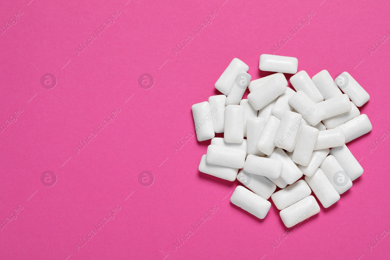 Photo of Tasty white chewing gums on pink background, top view