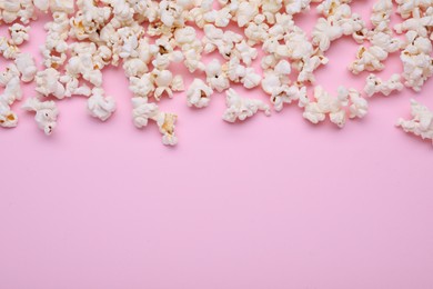 Photo of Tasty popcorn scattered on pink background, space for text