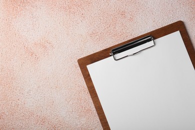 Photo of New clipboard with sheet of blank paper on color textured table, top view. Space for text