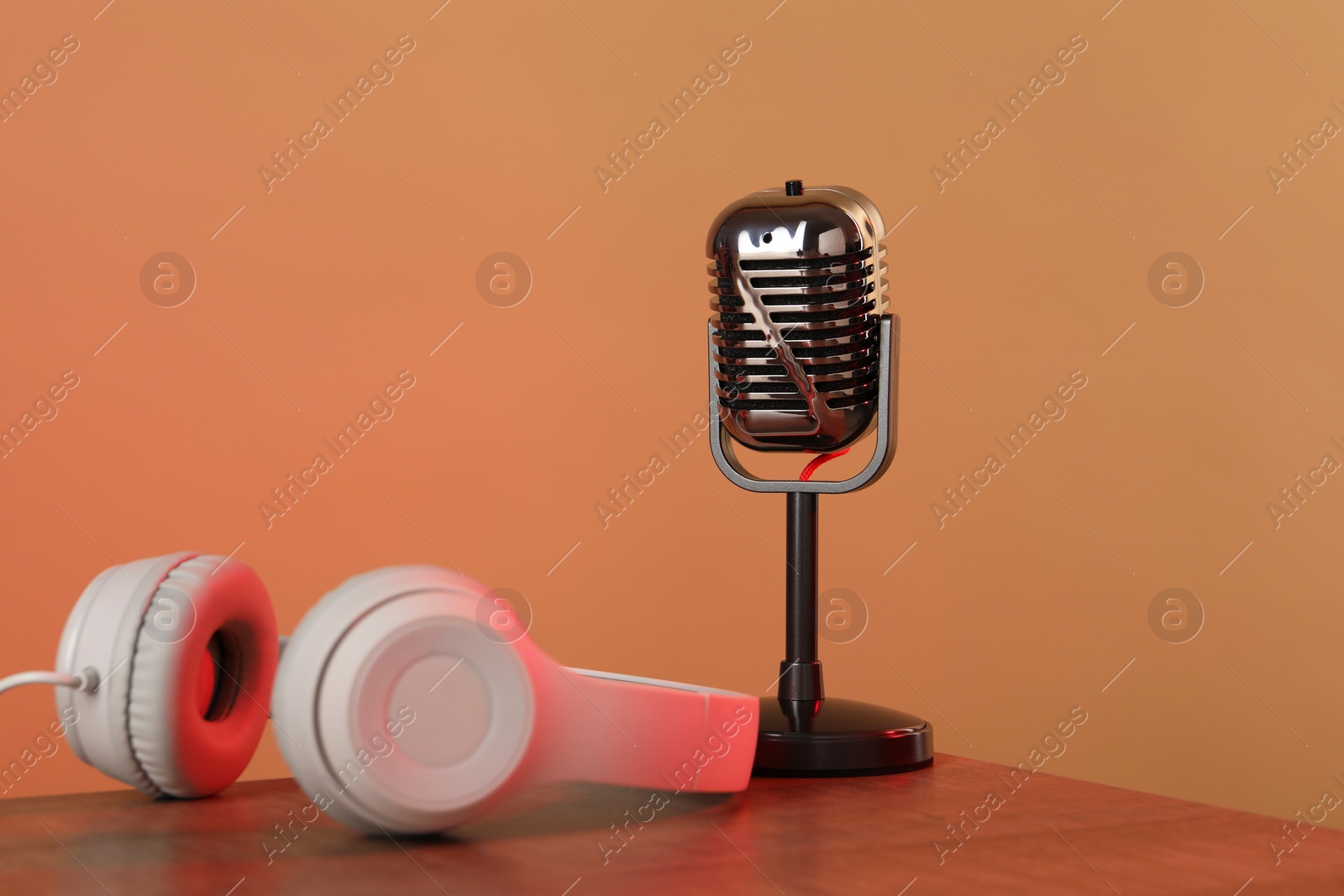 Photo of Vintage microphone and headphones on table against color background. Sound recording and reinforcement