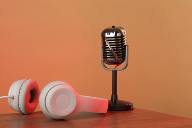 Photo of Vintage microphone and headphones on table against color background. Sound recording and reinforcement