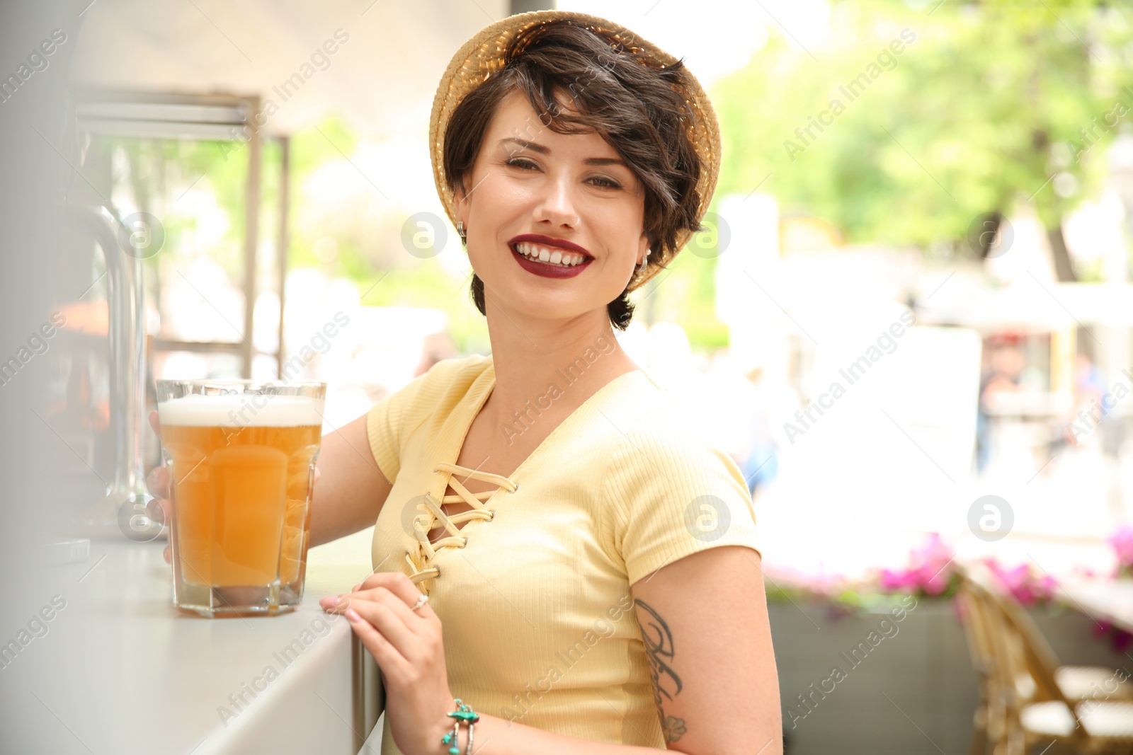 Photo of Young woman with glass of cold beer near bar counter