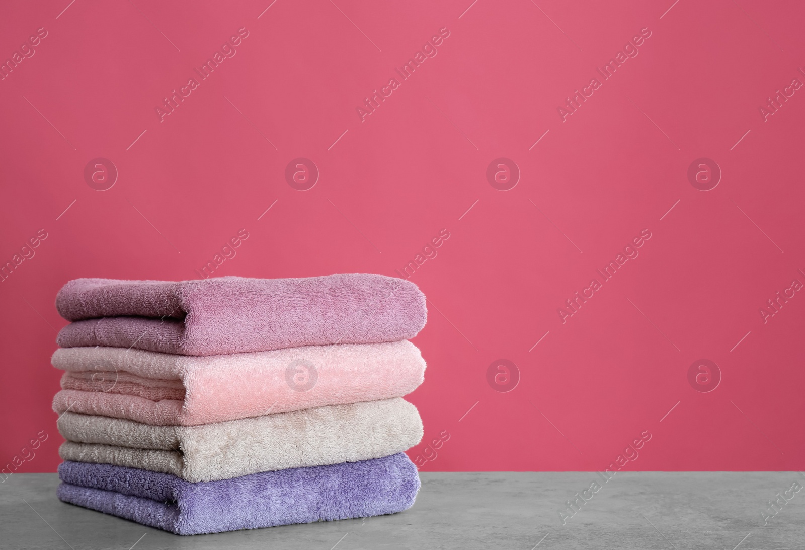 Photo of Stack of color towels on light grey stone table. Space for text