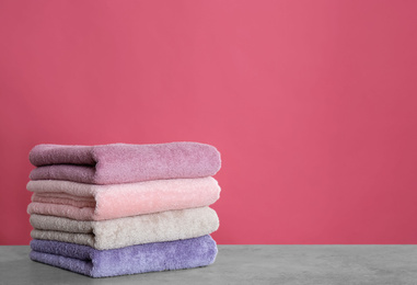 Stack of color towels on light grey stone table. Space for text