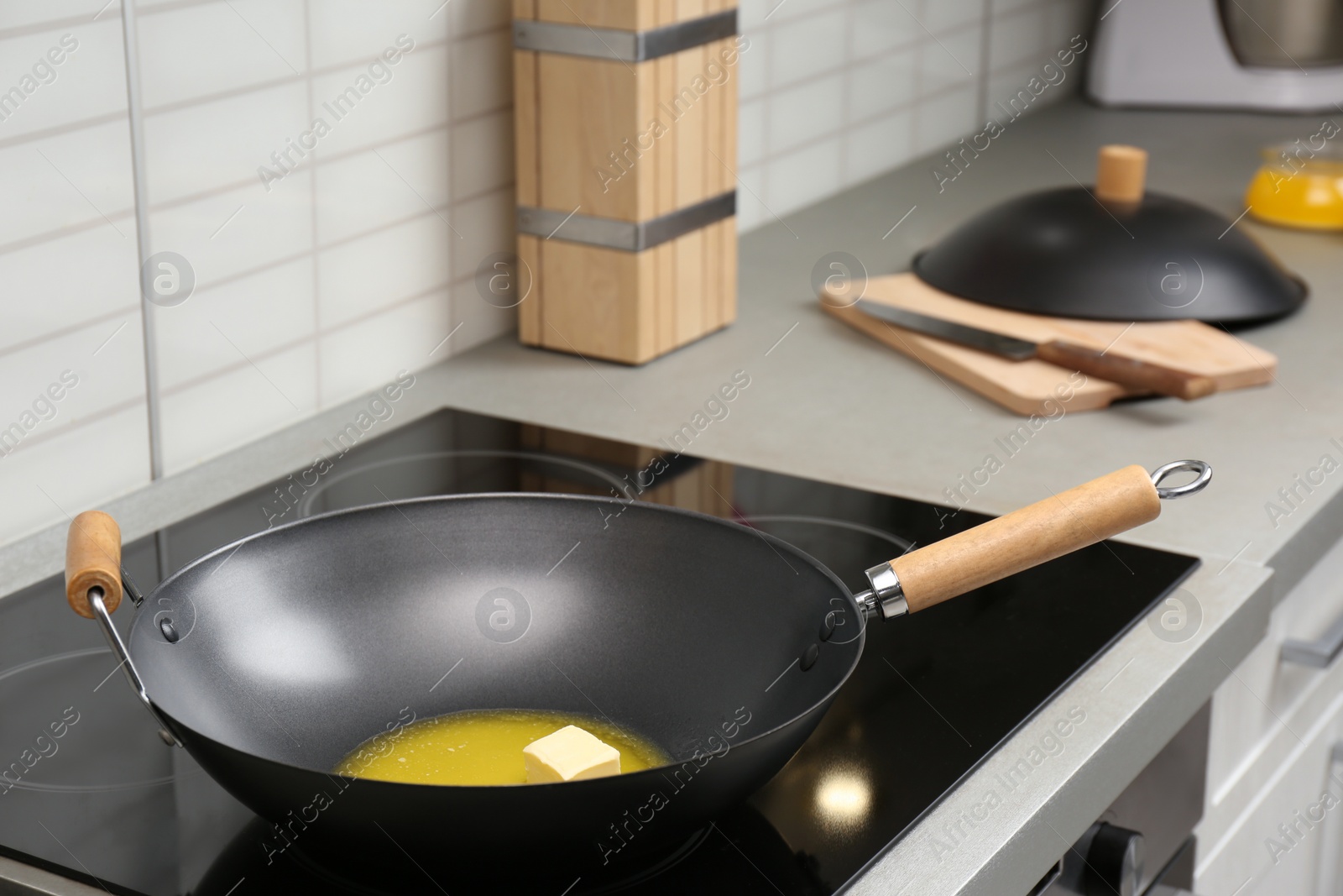 Photo of Wok pan with melted butter on stove in kitchen