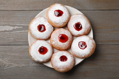 Photo of Hanukkah doughnuts with jelly and sugar powder served on wooden table, top view