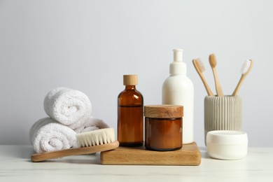 Photo of Different bath accessories and personal care products on light marble table against white wall
