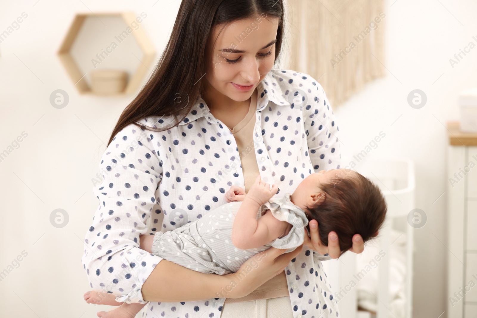 Photo of Mother with her sleeping newborn baby at home