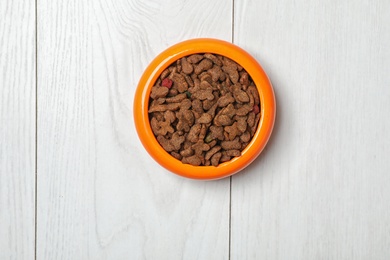 Bowl with food for cat or dog on wooden background. Pet care