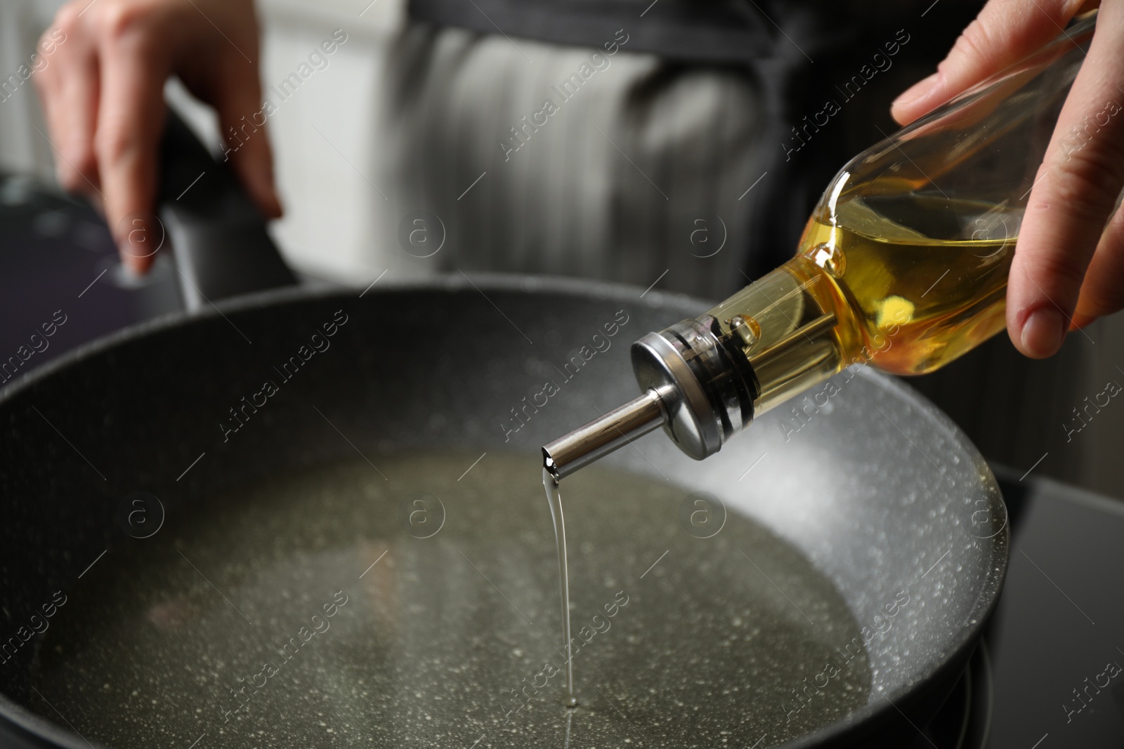 Photo of Woman pouring cooking oil from bottle into frying pan, closeup