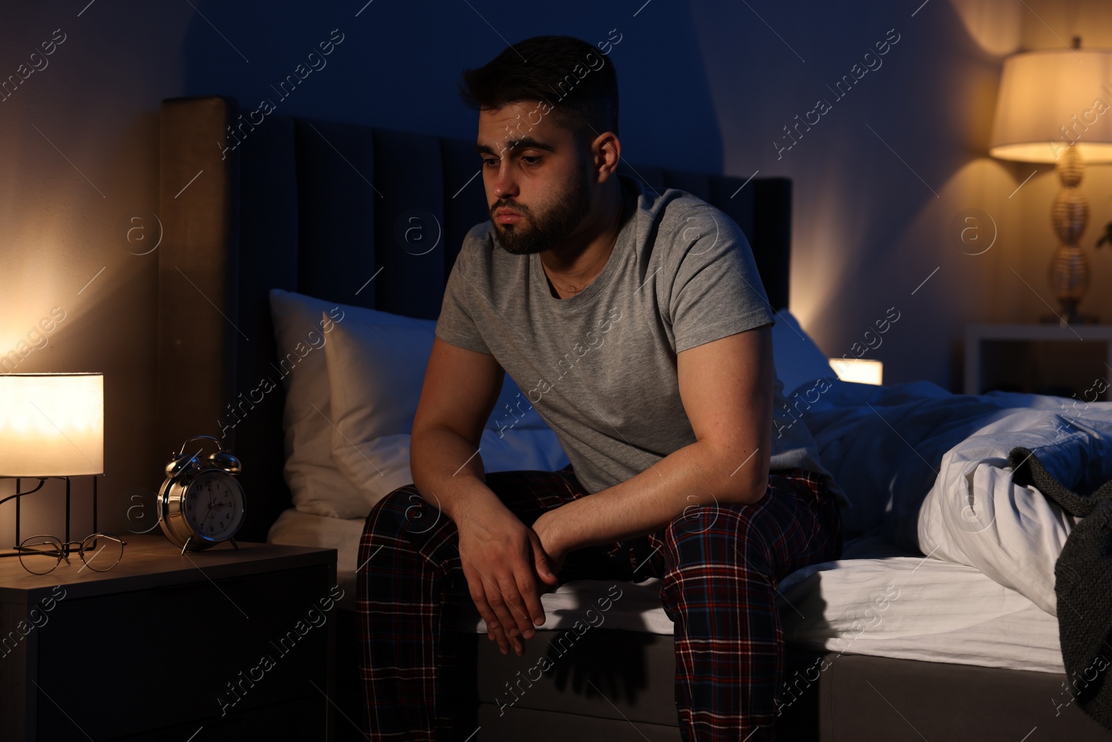 Photo of Frustrated man suffering from insomnia on bed