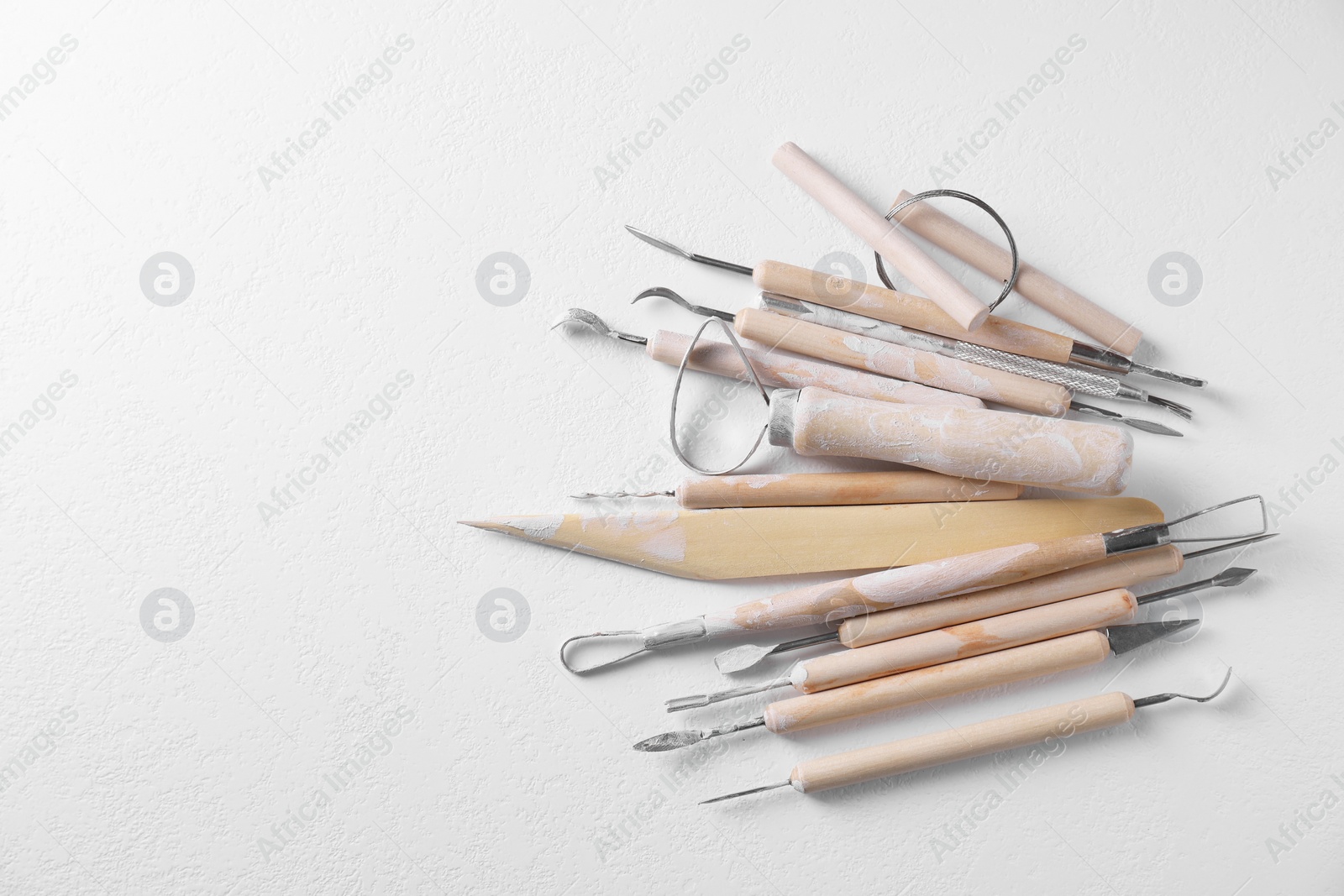 Photo of Set of different clay crafting tools on white table, top view. Space for text