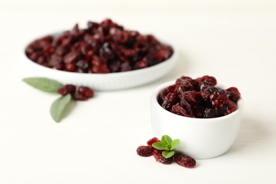 Photo of Tasty dried cranberries and leaves on white table. Space for text