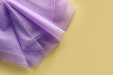 Photo of Beautiful tulle fabric on yellow background, top view. Space for text