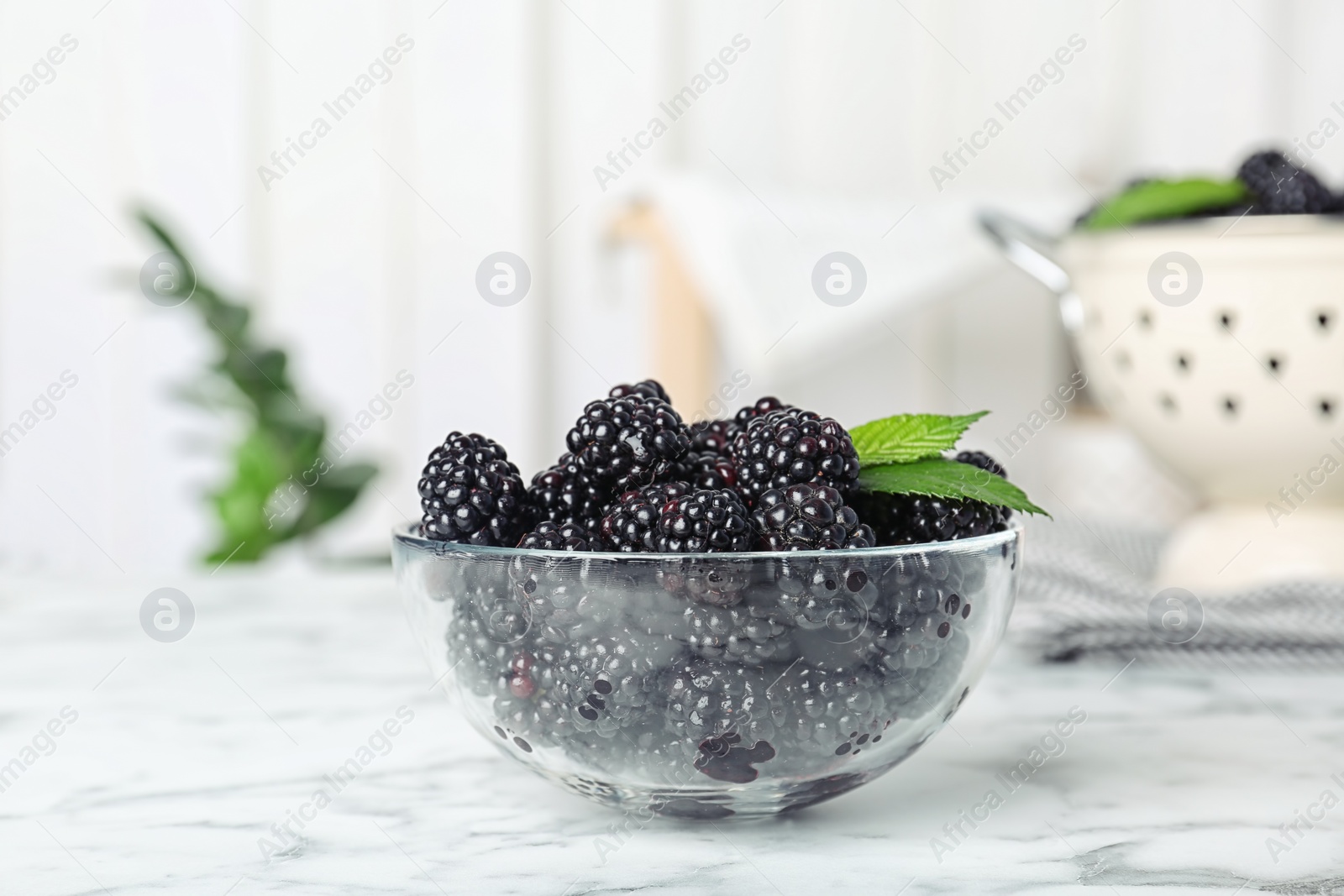 Photo of Bowl with fresh blackberry on marble table