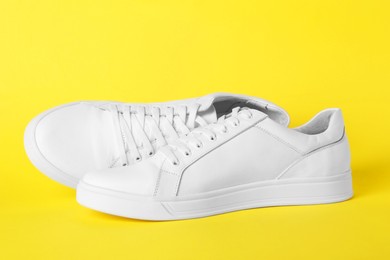 Photo of Pair of stylish white sneakers on yellow background