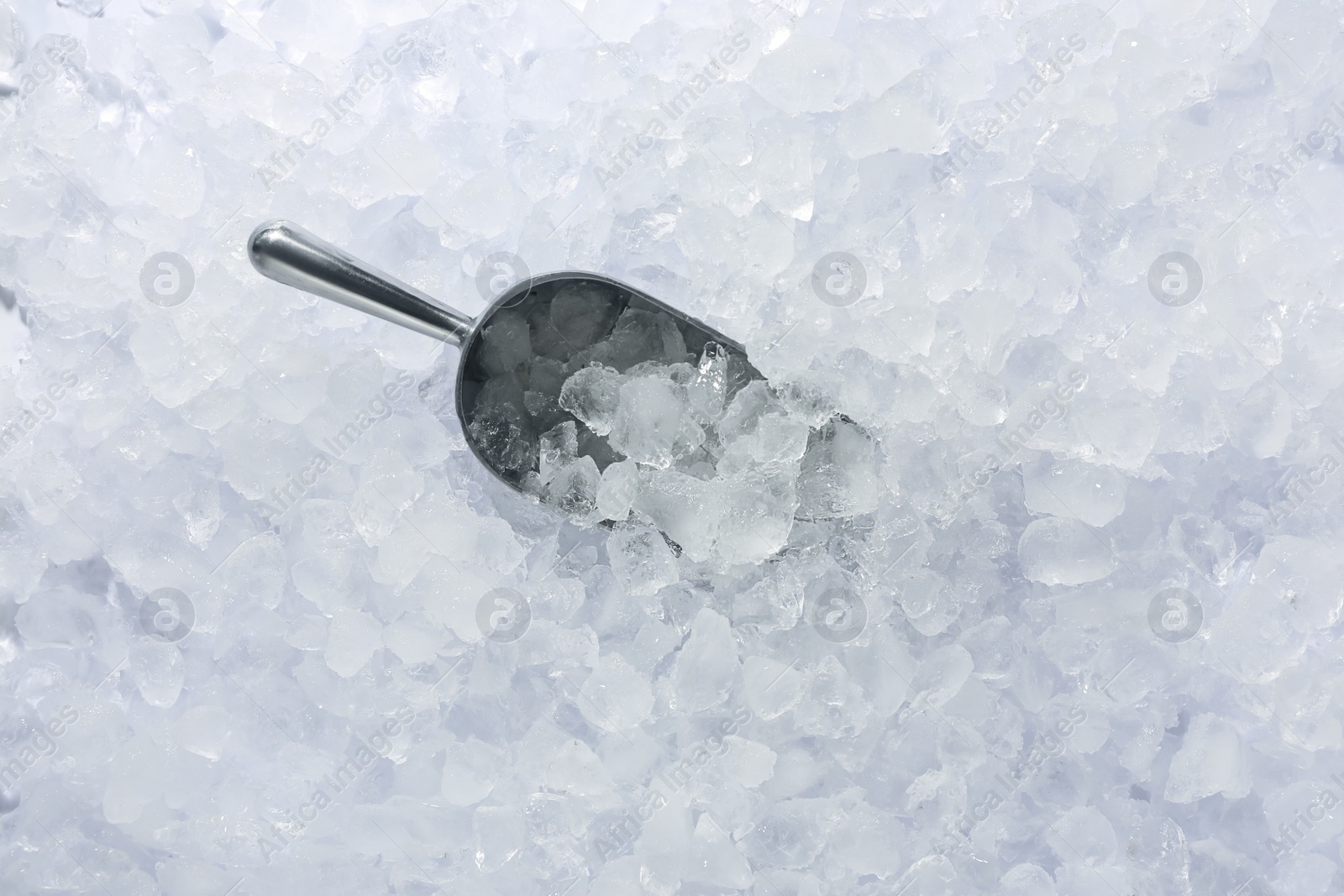 Photo of Metal scoop on crushed ice, top view