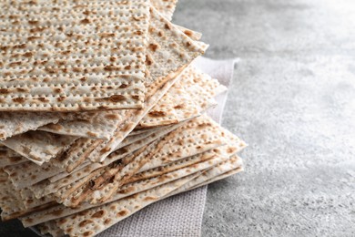 Photo of Stack of traditional matzos on grey table, closeup. Space for text