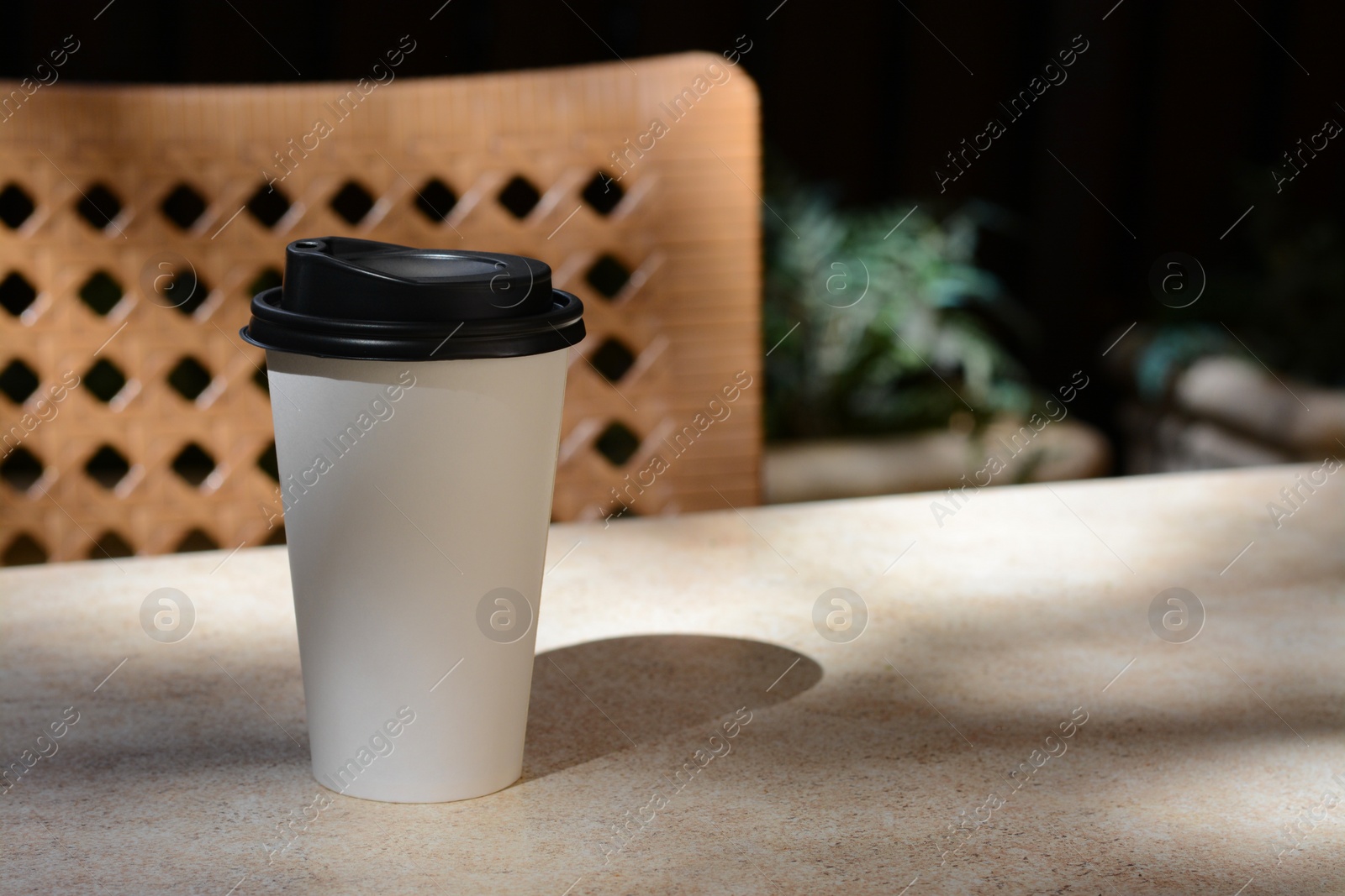 Photo of Takeaway coffee cup on beige table in cafe, space for text