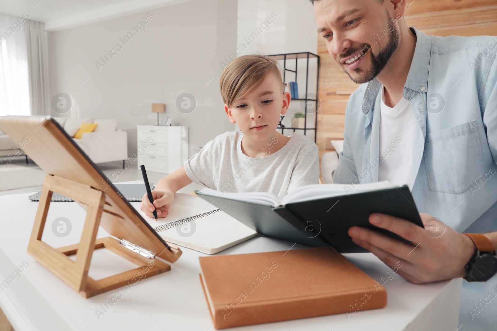 Photo of Boy with father doing homework at table indoors