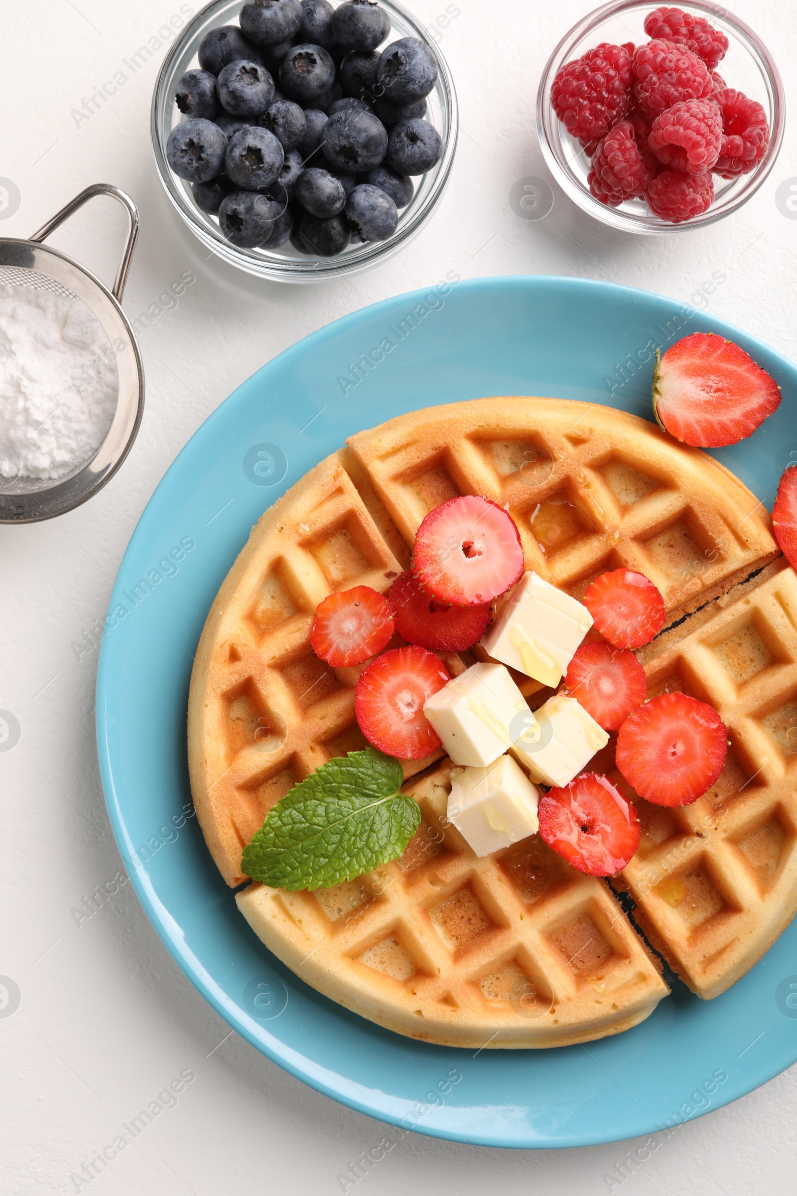 Photo of Tasty Belgian waffle with fresh berries, cheese and honey on white table, flat lay
