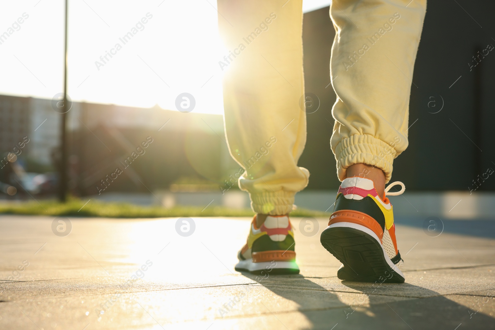 Photo of Woman walking in stylish sneakers outdoors, closeup. Space for text